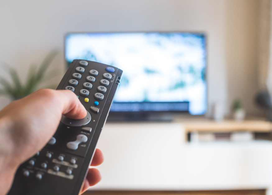 Graphic of a hand pointing a remote at a TV representing entertainment options at The Holt holiday cottage