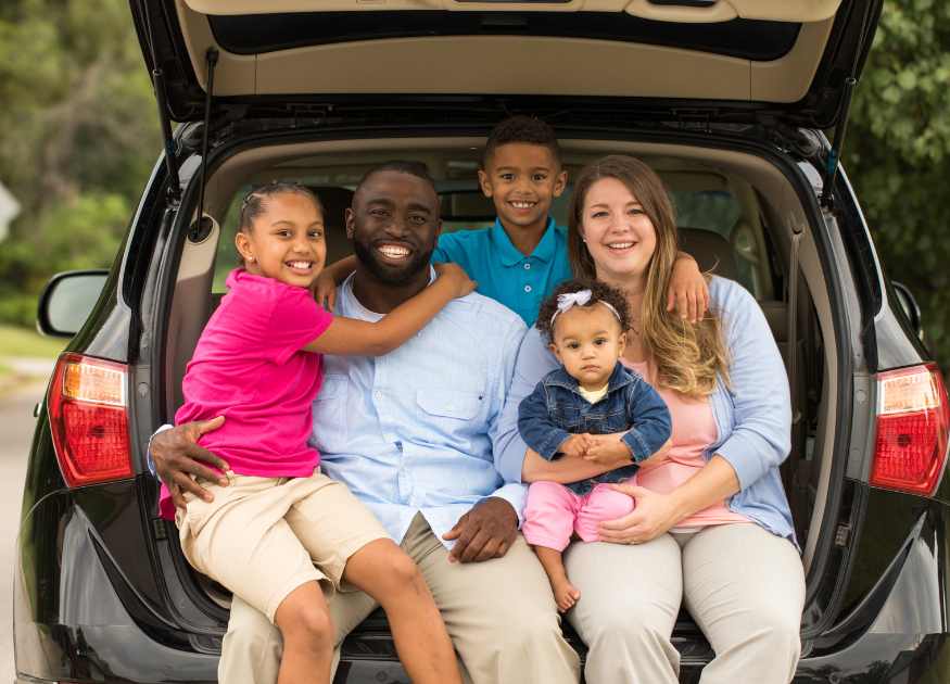 Graphic of a family with children smiling at the back of a car to represent facilities for families at The Holt holiday cottage