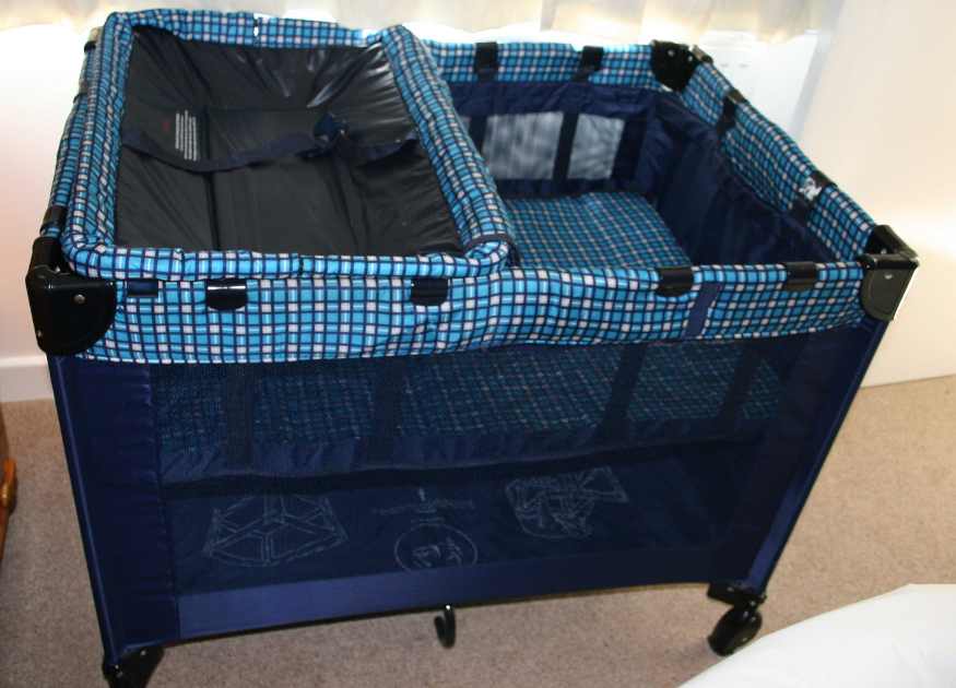 Image of a blue ttavel cot representing the bedding for families at The Holt holiday cottage