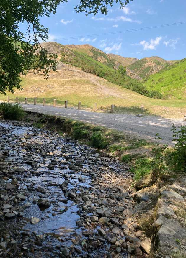 Image showing a brook at Cardingmill Valley. In the back of the shot are the hills of The Long Mynd. This is taken a few minutes walk from The Holt holiday cottage