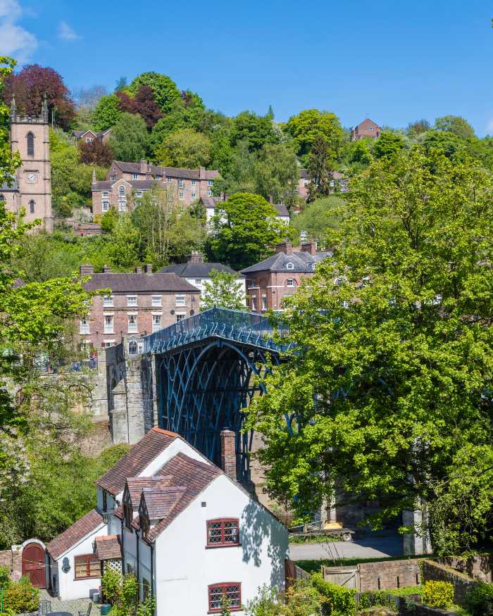Image of Ironbridge Gorge, showing the bridge, some pretty buildings and a church tower in the rear.